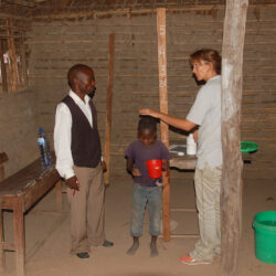 African child being measured for height by SCORE team member
