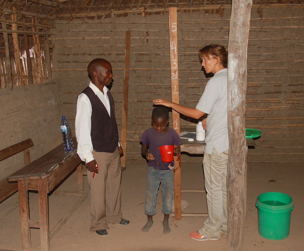 African child being measured for height by SCORE team member